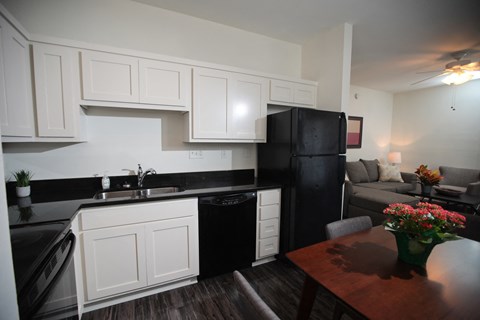 a kitchen and living room with a black refrigerator and a table